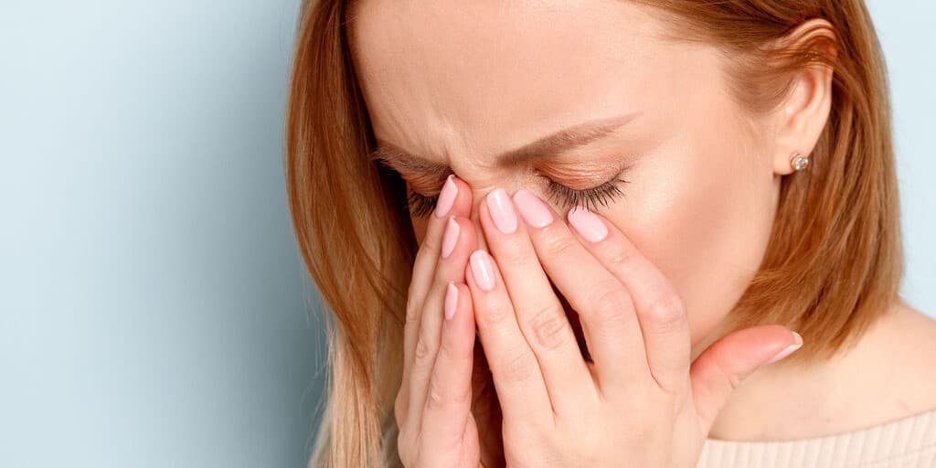 kobieta zakrywająca twarz w dłoniach, ponieważ ma opuchnięte oczy